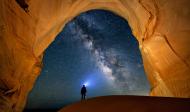 Das Foto zeigt einen Mann in einer Höhle vor Sternenhimmel Wundersame Freiheit