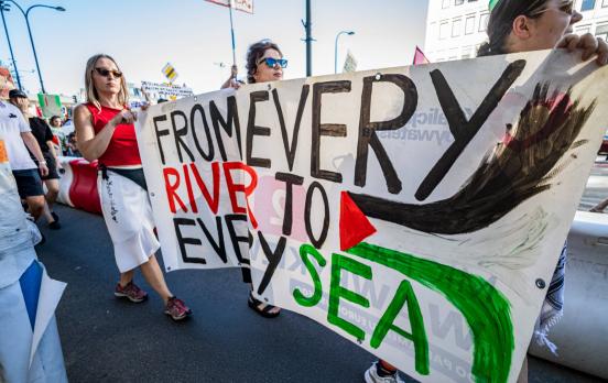 Das Foto zeigt mehrere Frauen mit einem Plakat mit der Aufschrift "From every river to every sea"