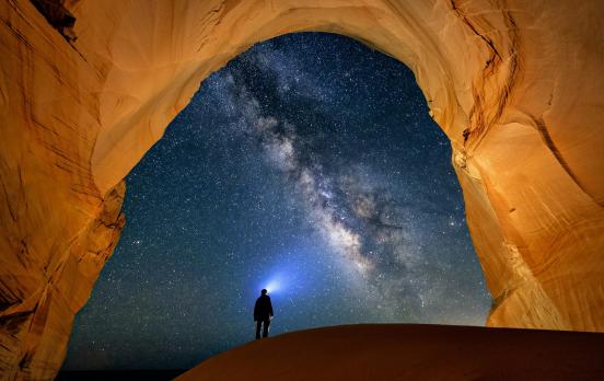 Das Foto zeigt einen Mann in einer Höhle vor Sternenhimmel
